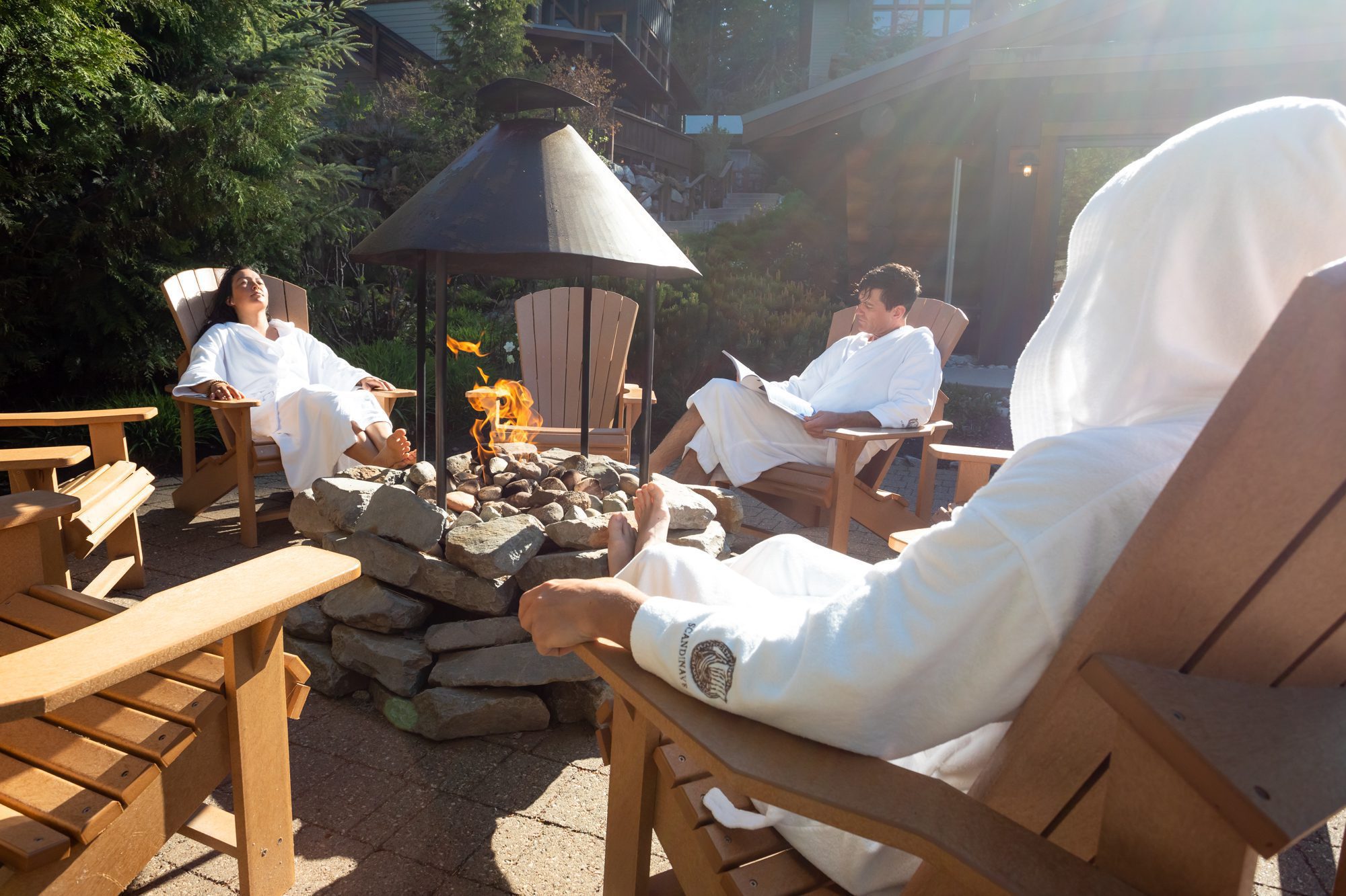 A group of people in robes sits by an outdoor firepit