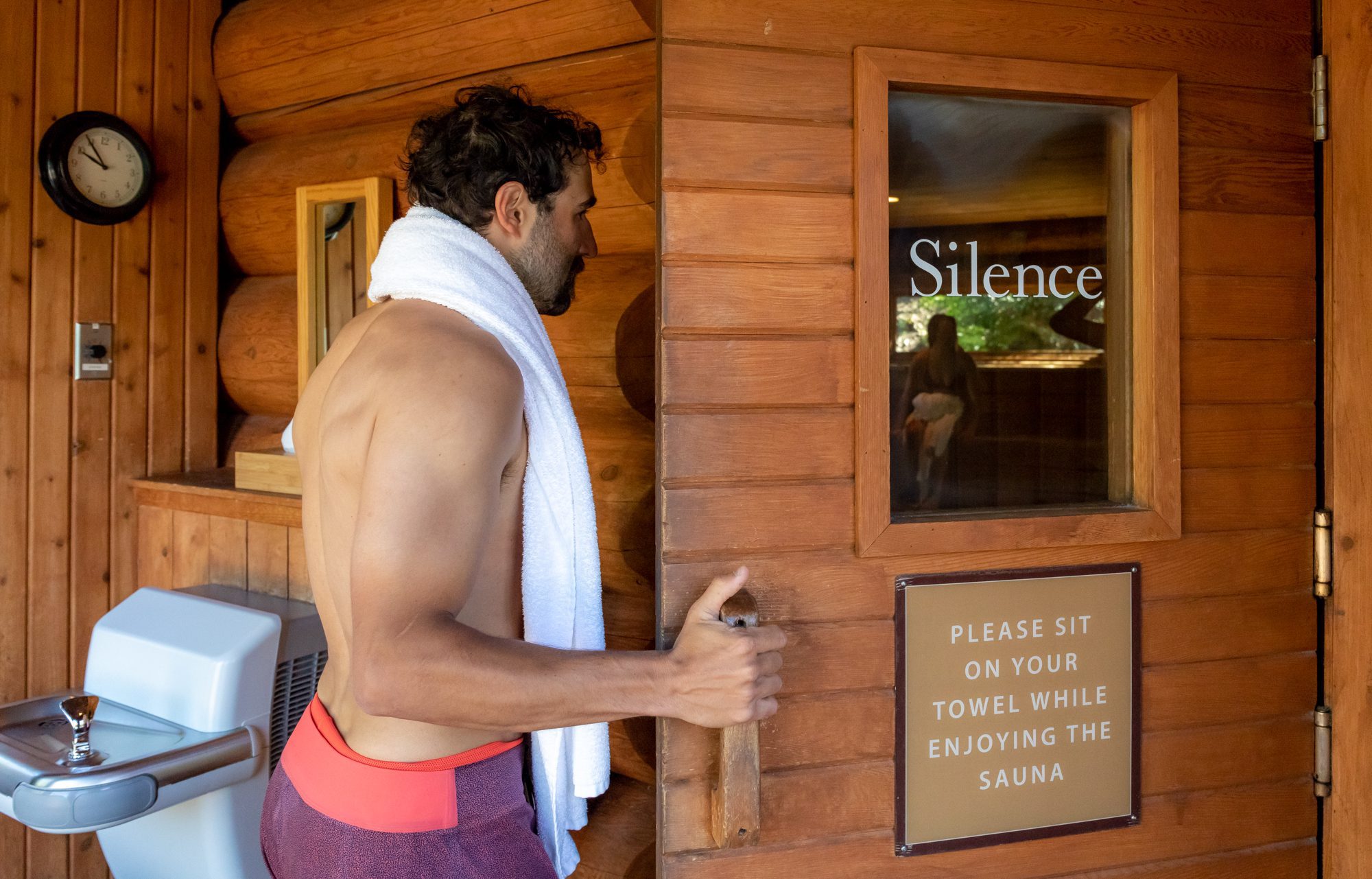 Man opening sauna door with silence printed on the glass